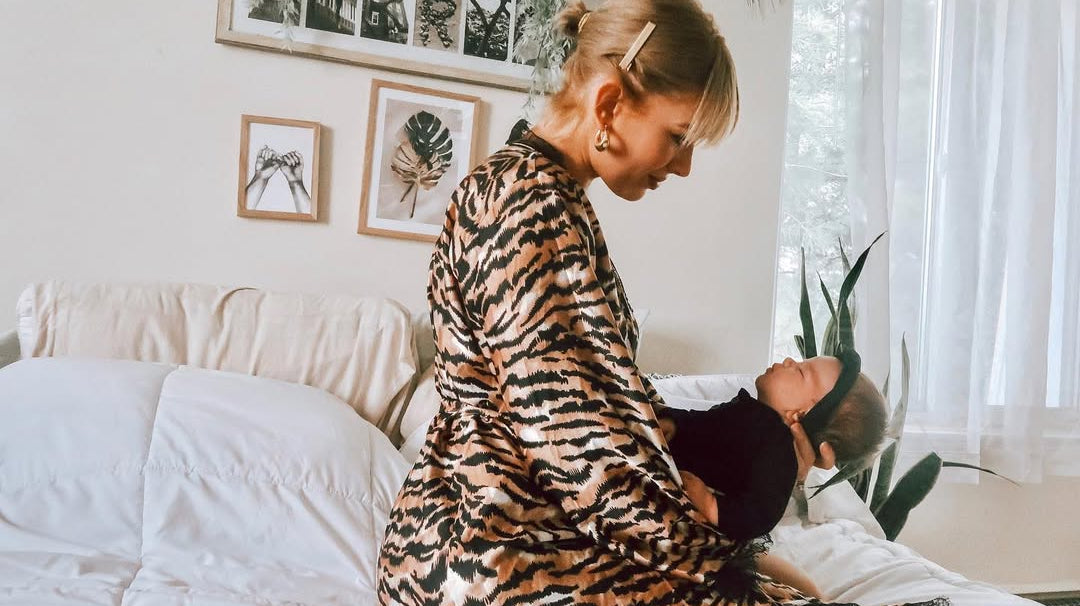 Model Kasha Marie Perry holding her baby, wearing a striped lounge robe