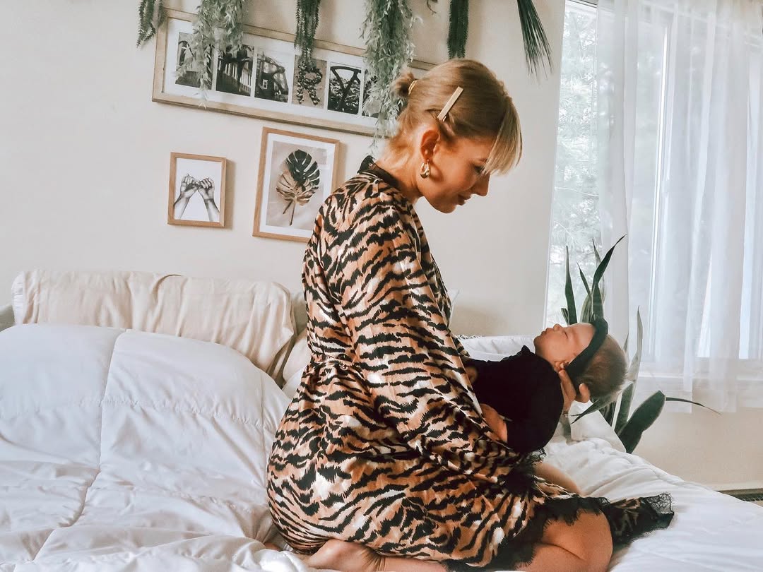 Model Kasha Marie Perry holding her baby, wearing a striped lounge robe